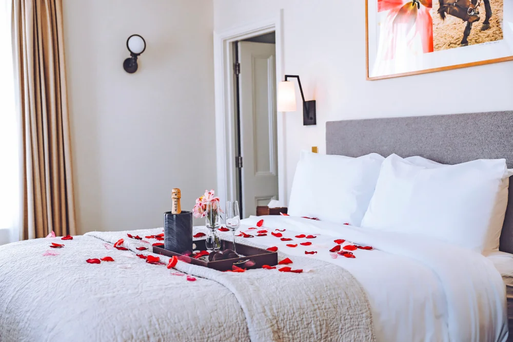 a bed with a bottle of champagne and rose petals on it